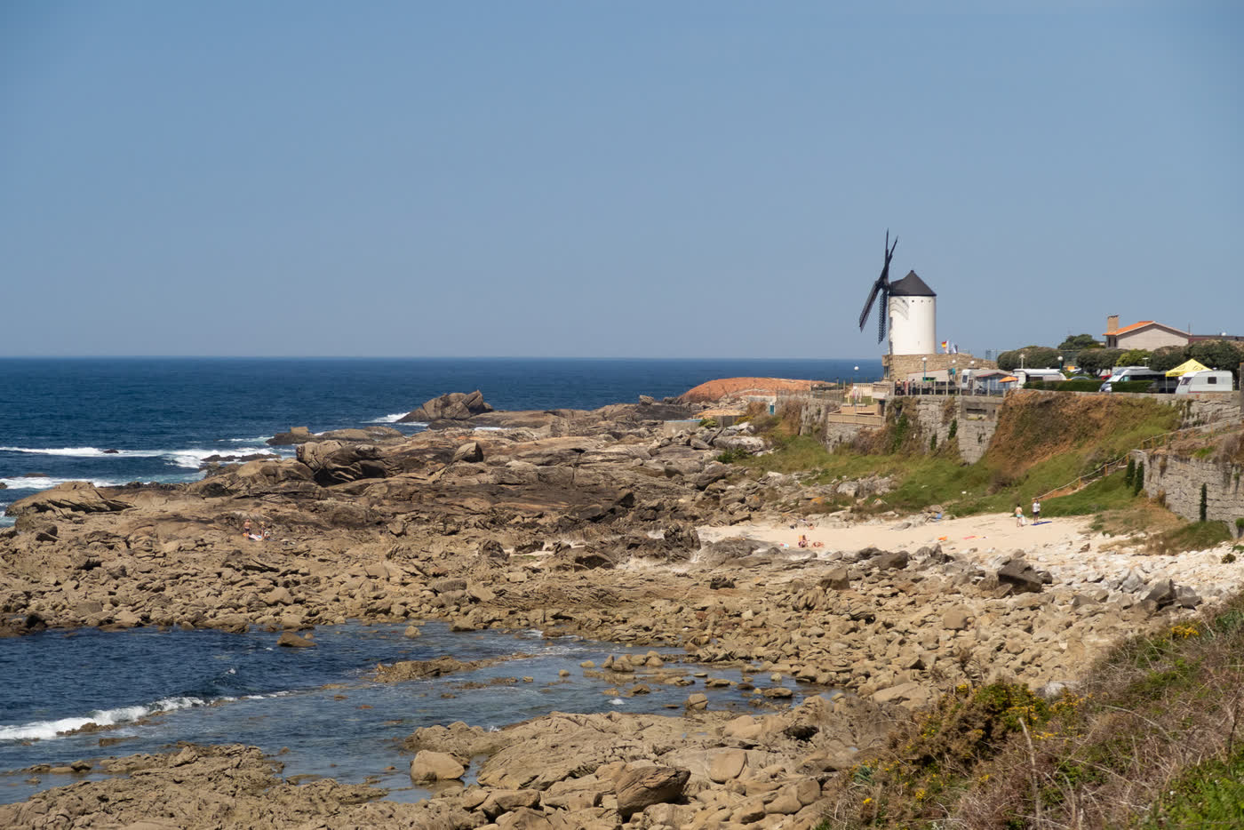A windmill above a rocky Atlantic beach
